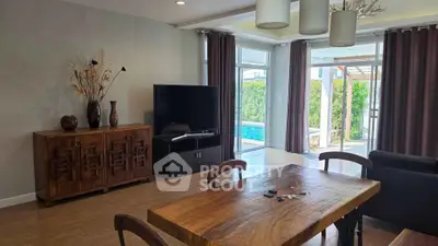 Spacious living room with pool view, elegant wooden furniture, and modern decor in a luxury home.