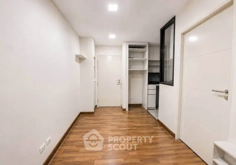 Modern minimalist apartment hallway with wooden flooring and white walls