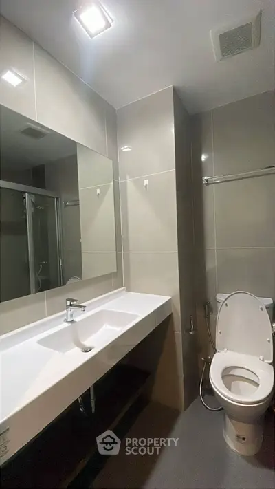 Modern bathroom with sleek fixtures and large mirror in contemporary apartment.