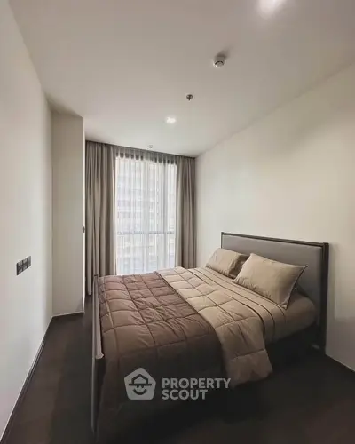 Modern bedroom with large window and elegant bedding in a stylish apartment.