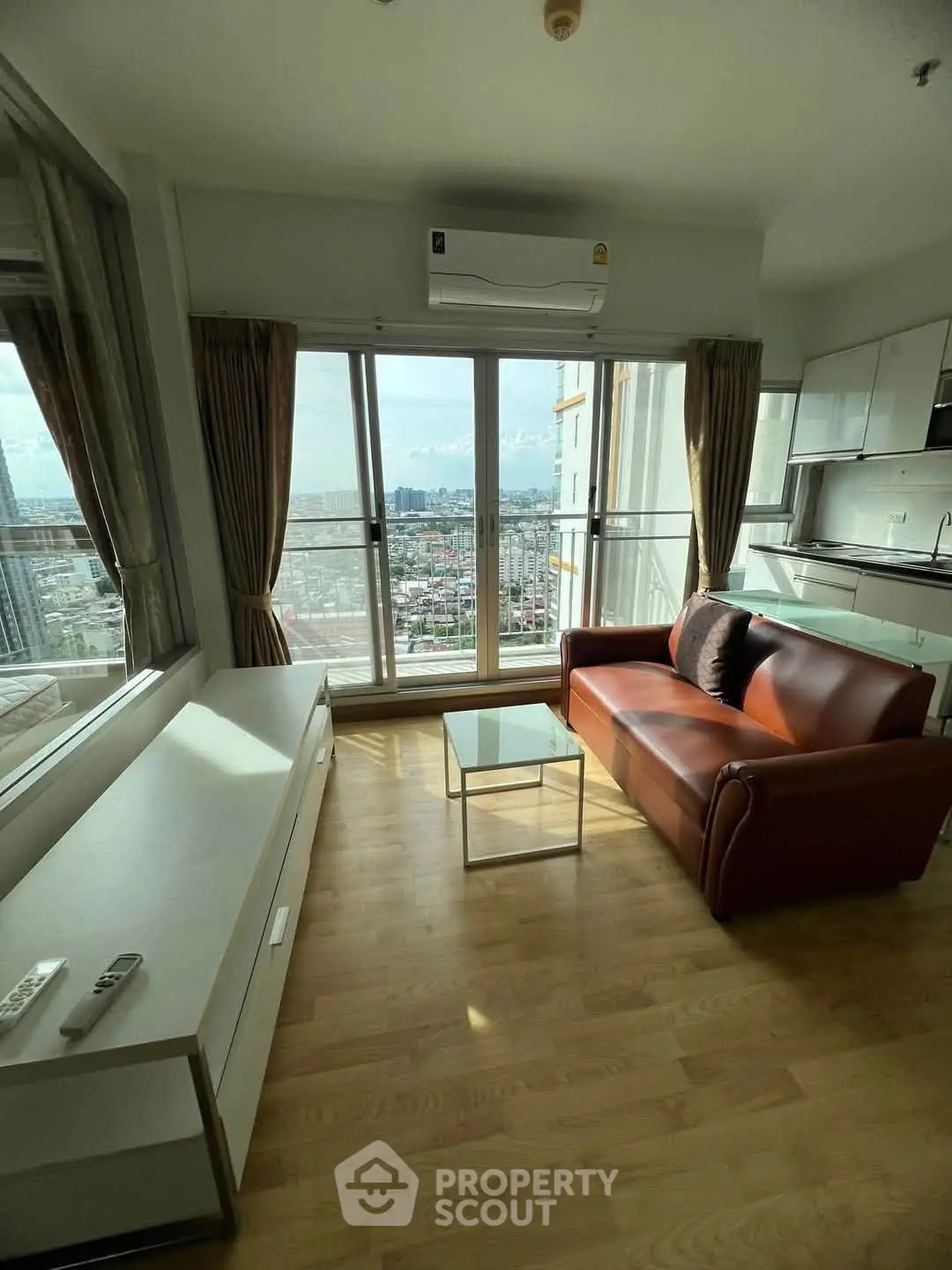 Modern living room with city view, featuring sleek furniture and large windows for natural light.
