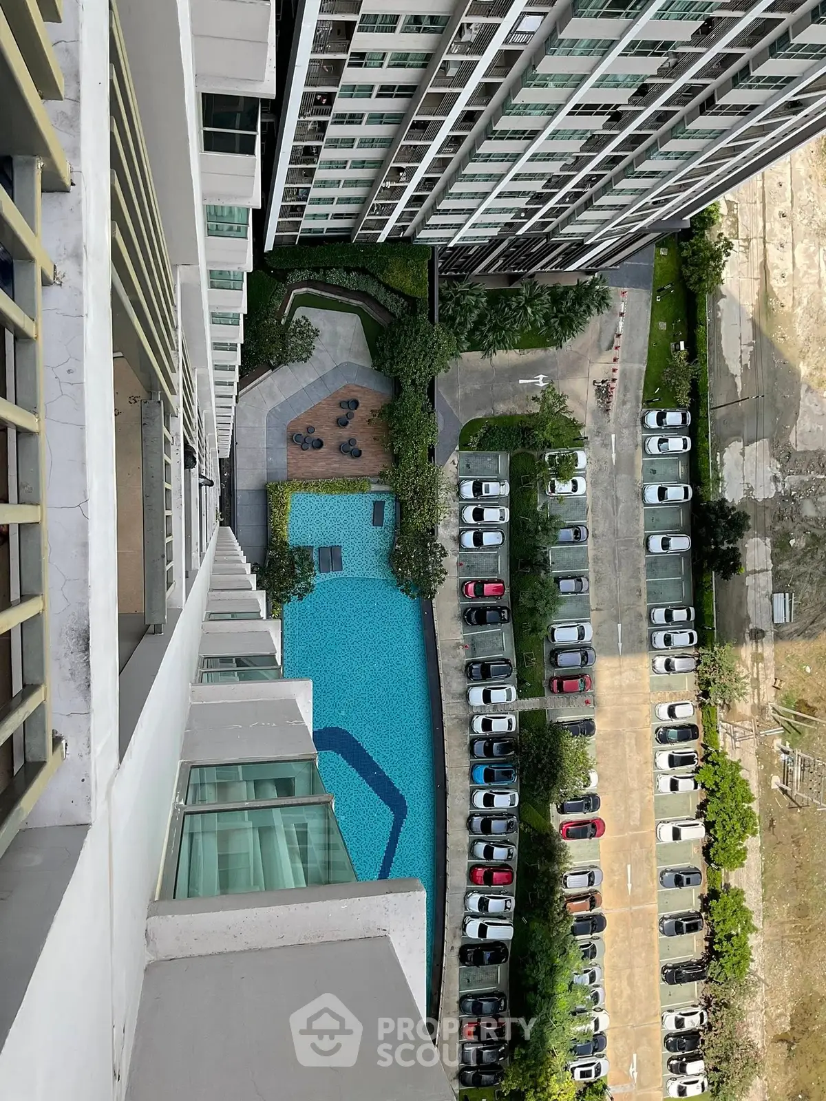 Stunning aerial view of modern condominium with pool and parking area, perfect urban living.