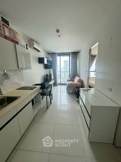 Modern apartment interior with open kitchen and living area, featuring city view from balcony.