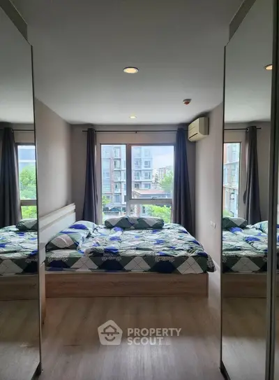 Modern bedroom with large windows and mirrored closets in urban apartment.