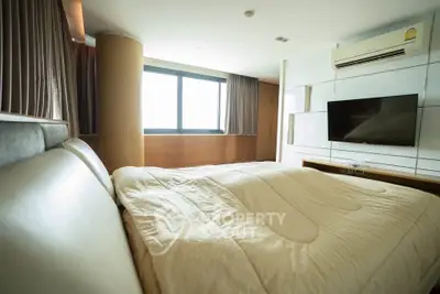 Spacious bedroom with modern decor and large window for natural light.