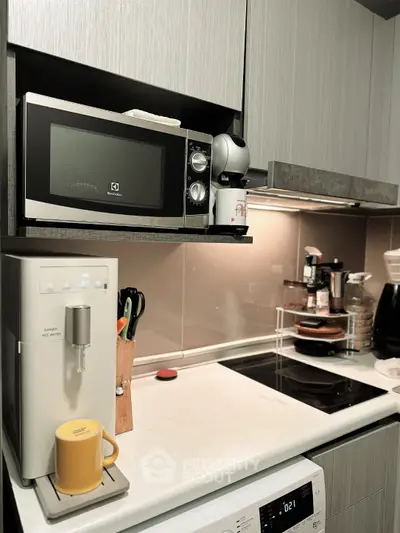 Modern kitchen with sleek appliances and stylish cabinetry, featuring a microwave, coffee maker, and induction cooktop.