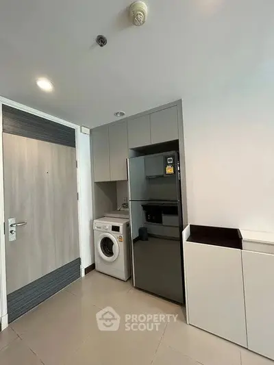 Modern kitchen with sleek appliances and washing machine in compact layout
