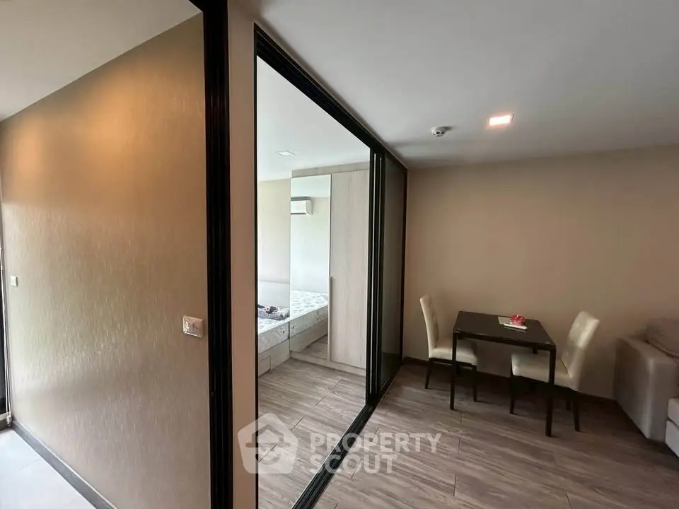 Modern apartment interior with cozy dining area and bedroom view, featuring sleek design and warm lighting.