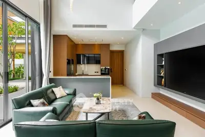 Luxurious modern living room with open kitchen, sleek design, and large windows overlooking greenery.