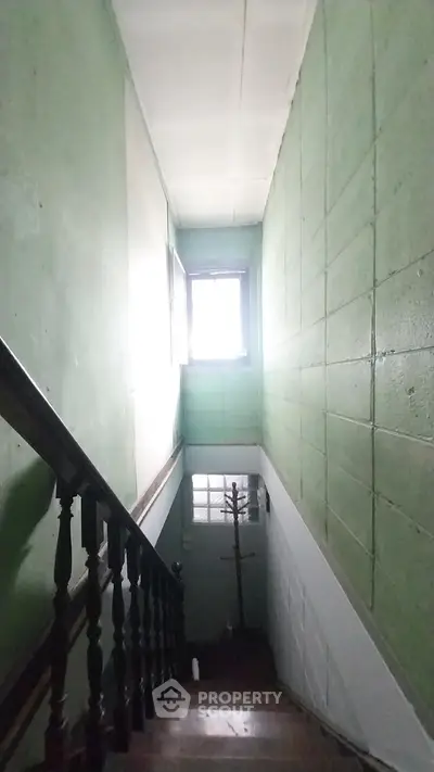 Narrow staircase with green walls and natural light from window