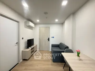 Modern living room with sleek furniture and wooden flooring, featuring a cozy sofa and flat-screen TV.
