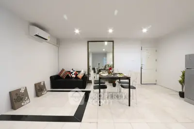 Modern living room with sleek dining area and stylish decor, featuring a black sofa and elegant table setting.