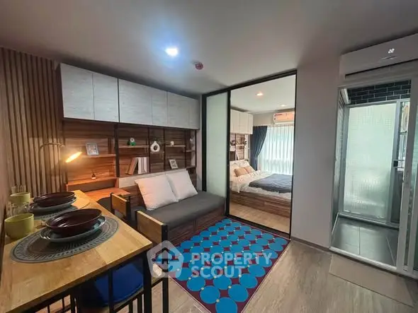 Modern studio apartment with cozy living area and bedroom separated by glass partition.