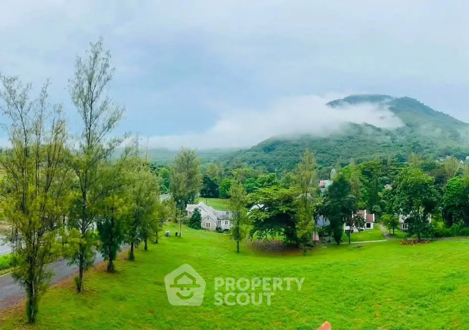 Scenic view of lush green landscape with houses and misty mountains in the background.