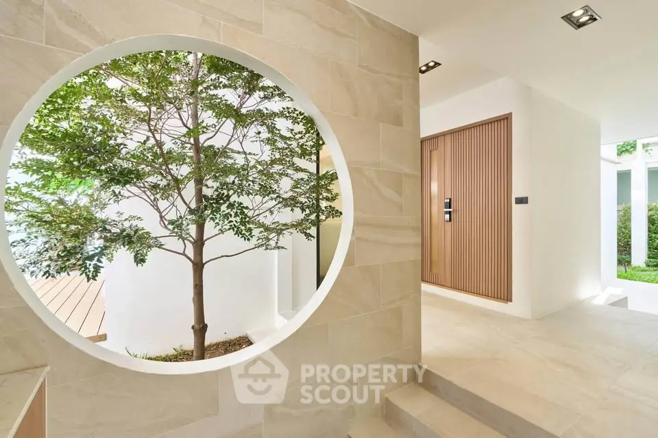 Modern minimalist entrance with circular window and lush greenery