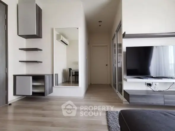 Modern living room with sleek furniture and large TV, showcasing minimalist design.