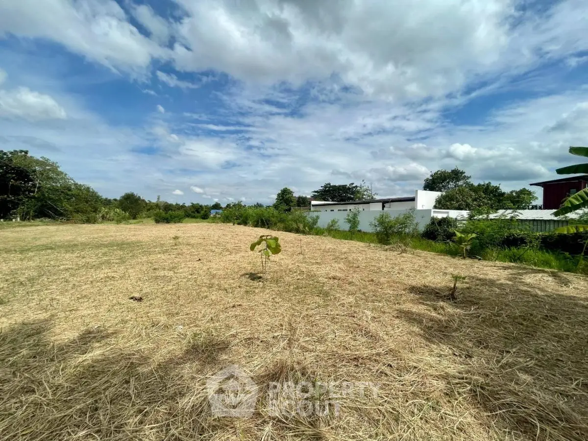 Expansive plot of land with lush greenery and clear skies, ideal for development opportunities.