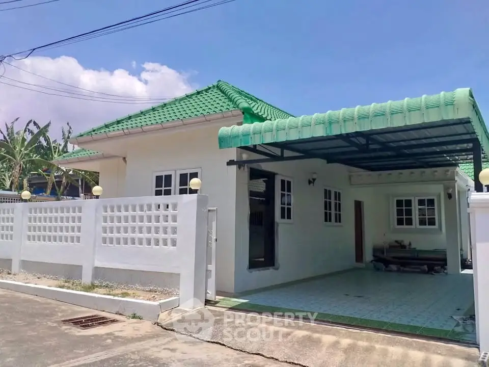 Charming single-story home with green roof and spacious carport in a serene neighborhood.