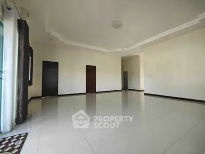 Spacious empty living room with large windows and elegant ceiling design.