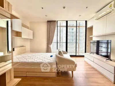 Modern bedroom with large windows and stylish furniture in a high-rise apartment.