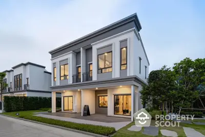 Modern two-story house with large windows and manicured lawn in a suburban neighborhood.