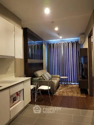 Modern living room with cozy sofa, stylish decor, and open kitchen layout in a chic apartment.