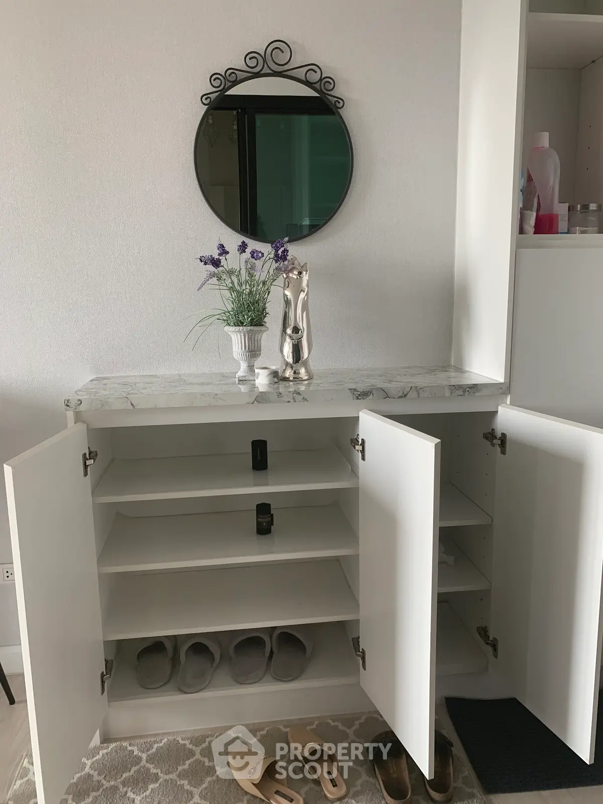 Stylish entryway with open shoe cabinet, decorative mirror, and elegant decor accents.