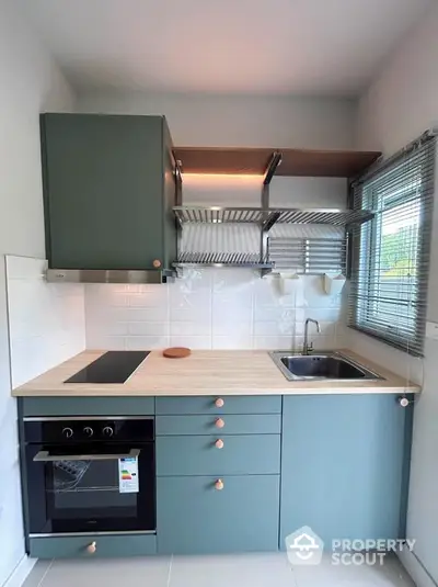 Modern kitchen with sleek cabinetry and built-in oven, featuring a minimalist design and ample natural light.