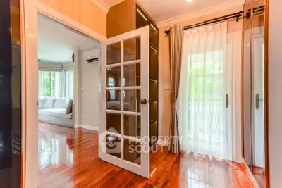 Elegant interior with polished wooden floors and glass door leading to a cozy living room and balcony.