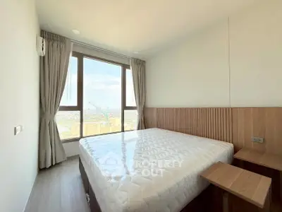 Bright bedroom with large window offering stunning city view, featuring modern decor and cozy ambiance.
