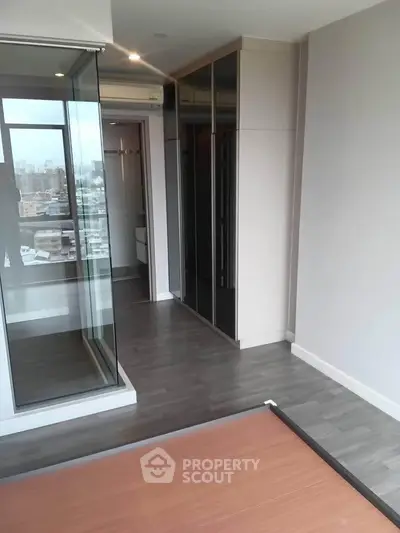 Modern apartment interior with sleek flooring and glass partition, offering a glimpse of the city view.