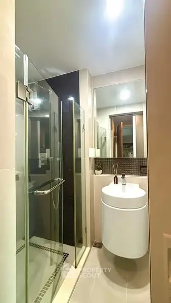 Modern bathroom with glass shower and sleek vanity in contemporary apartment.