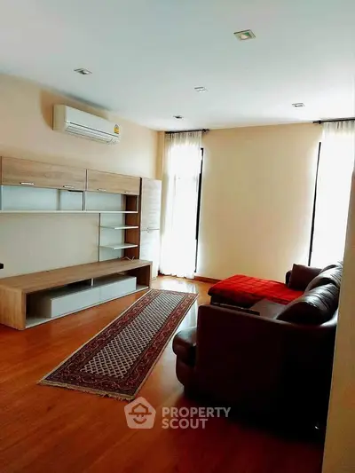 Spacious living room with modern furniture and wooden flooring.