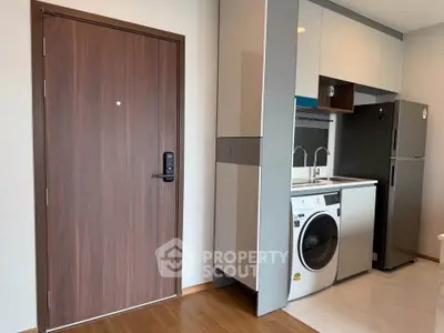 Modern apartment interior with washing machine and sleek kitchen appliances.