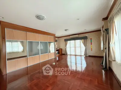 Spacious living room with wooden flooring and large windows for natural light.