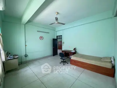 Spacious minimalist bedroom with single bed and desk, ideal for students or professionals.