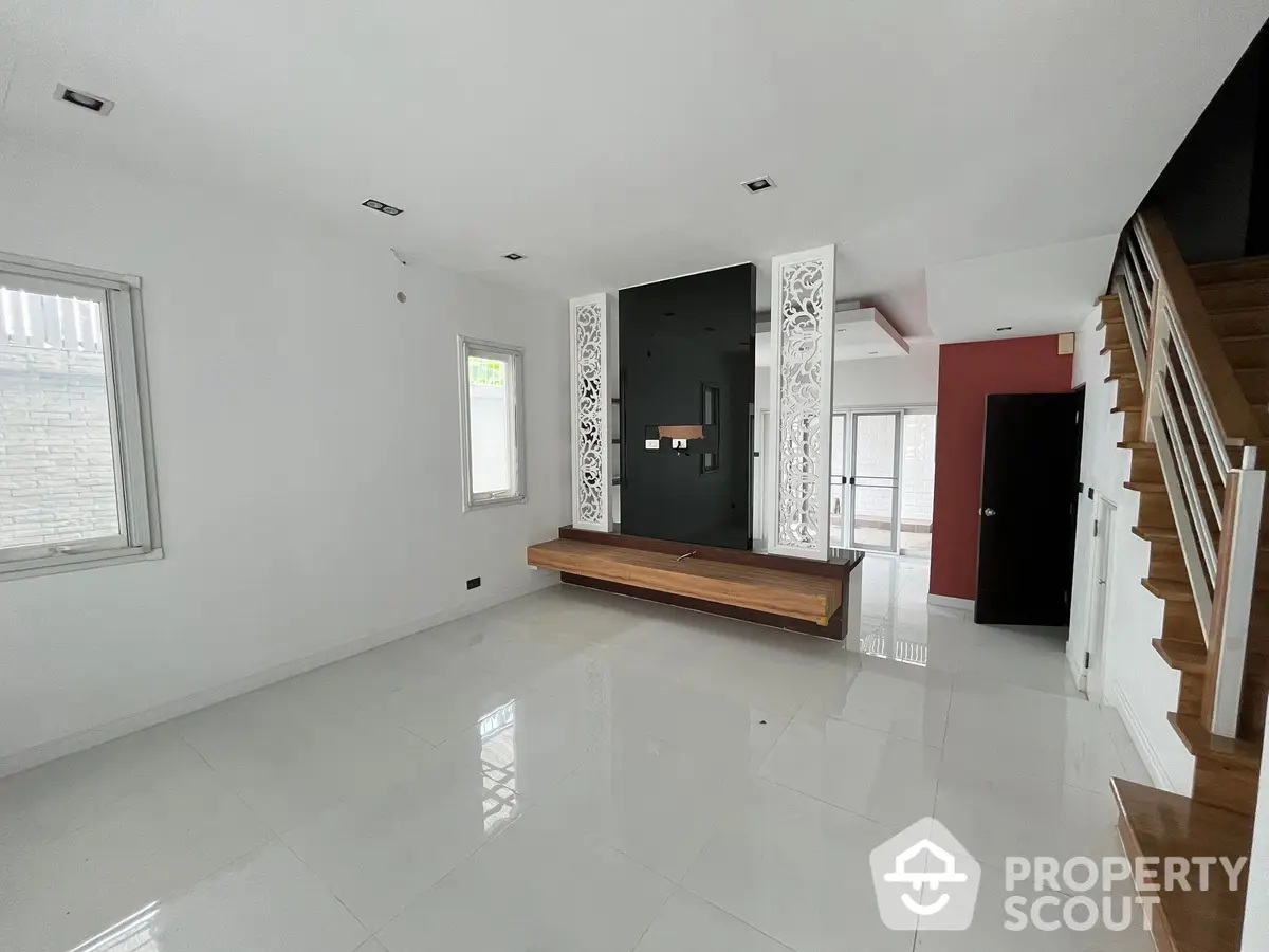 Spacious and bright living room with polished white tiles, elegant staircase, and modern decorative front door, perfect for stylish living.