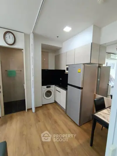 Modern kitchen with sleek appliances and wooden flooring in a stylish apartment.