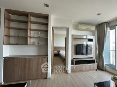 Modern living room with built-in wooden shelves and TV unit, leading to a cozy bedroom.