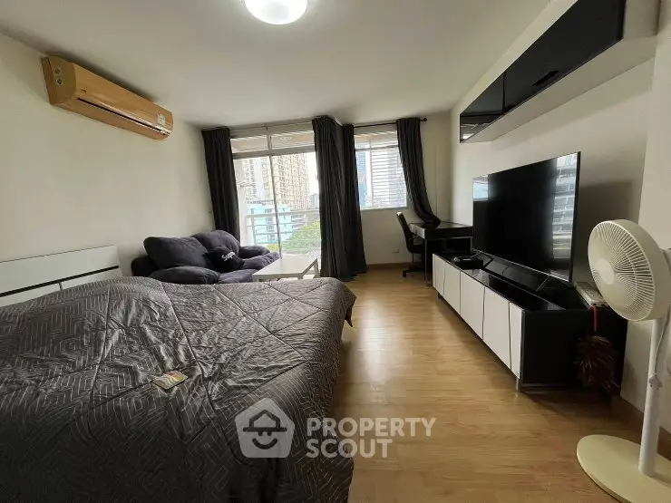 Spacious studio apartment with modern furnishings and large windows offering city views.