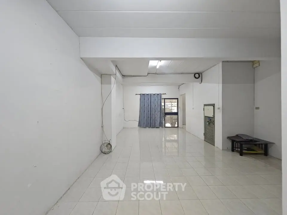Spacious empty room with tiled flooring and window view, ideal for customization.