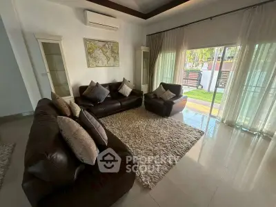 Luxurious living room with leather sofas and garden view, perfect for relaxation and entertaining.