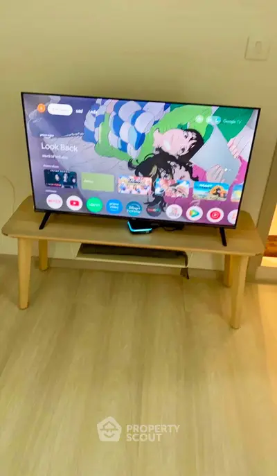Modern living room with sleek TV setup on wooden stand, showcasing a cozy and stylish interior design.