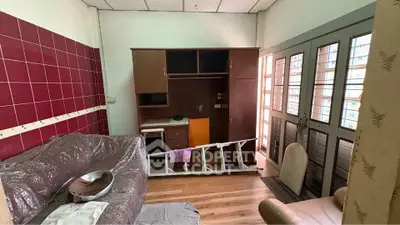 Cozy living room with natural light and wooden flooring, featuring a sofa and storage unit.