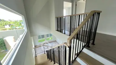 Modern staircase with sleek black railings and large window offering natural light