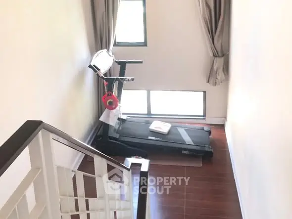 Bright home gym with treadmill and large windows for natural light.