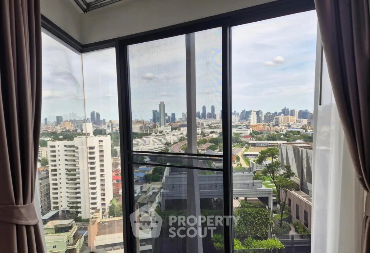 Stunning cityscape view from a high-rise apartment window, showcasing urban skyline and lush greenery.