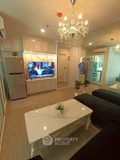 Elegant living room with chandelier, modern TV setup, and stylish furniture in a cozy apartment.