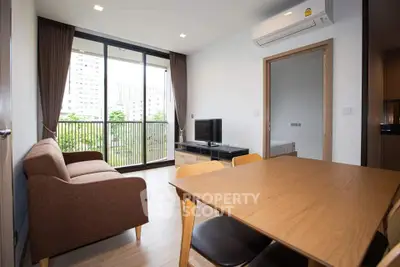 Modern living room with balcony view, featuring sleek furniture and ample natural light.