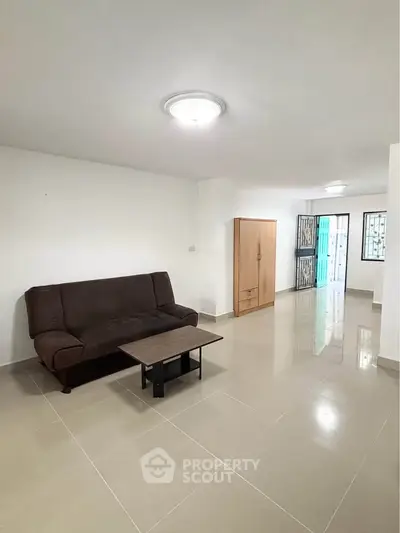 Spacious living room with modern sofa and sleek tile flooring in a bright apartment.